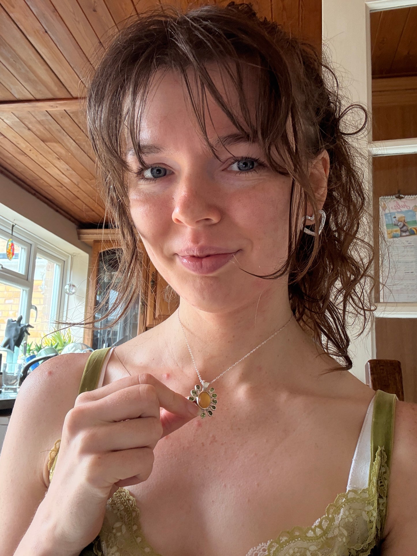 Woman wearing silver flower shaped necklace with yellow opals and peridot