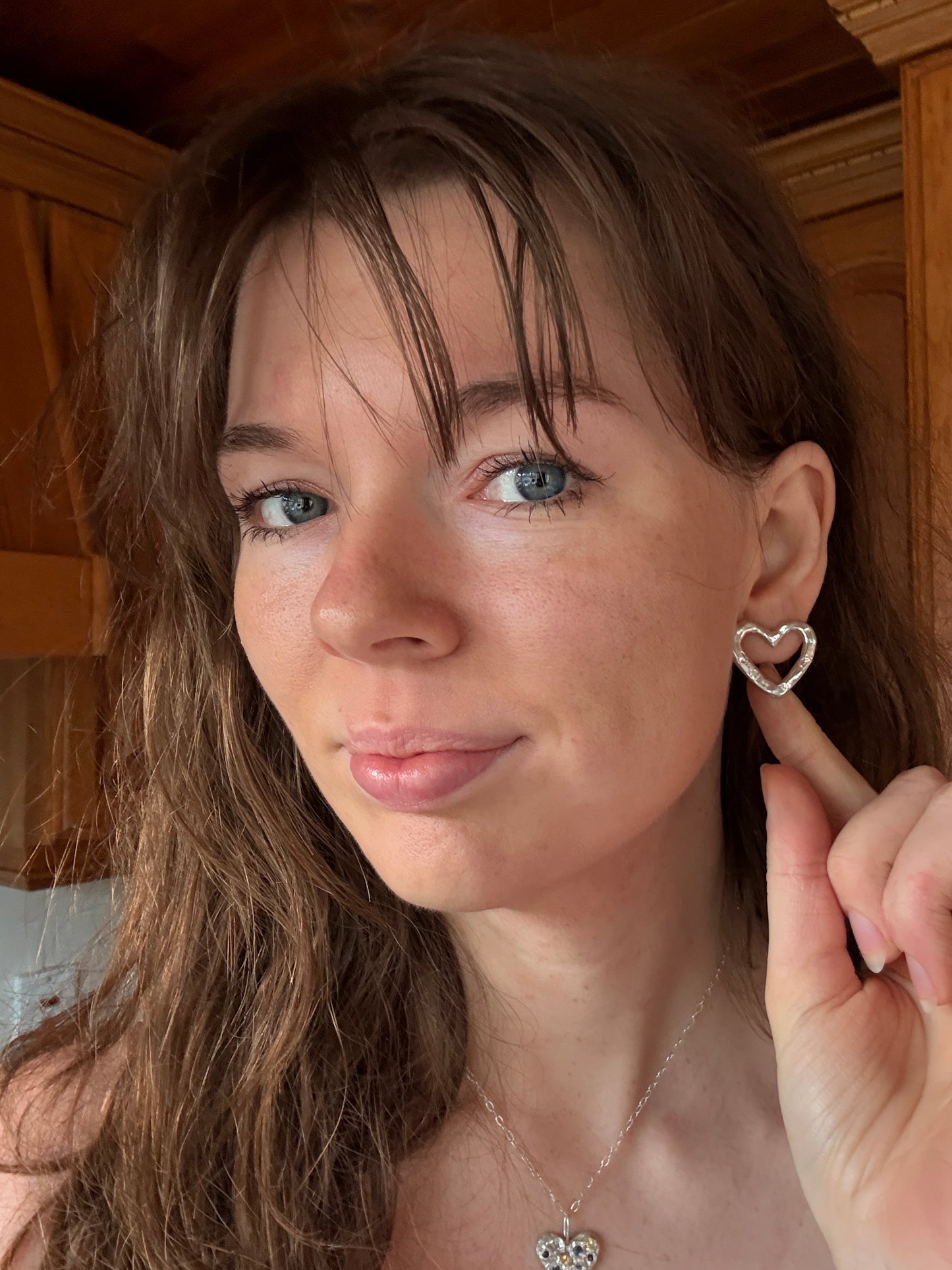 Silver Heart Stud Earrings on Woman Touching Ear
