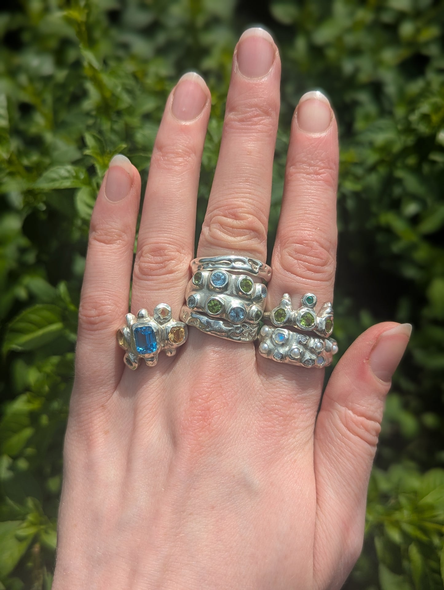 Silver bohemian rings with opals, pearls and green, blue and yellow gemstones and molten textured metal.