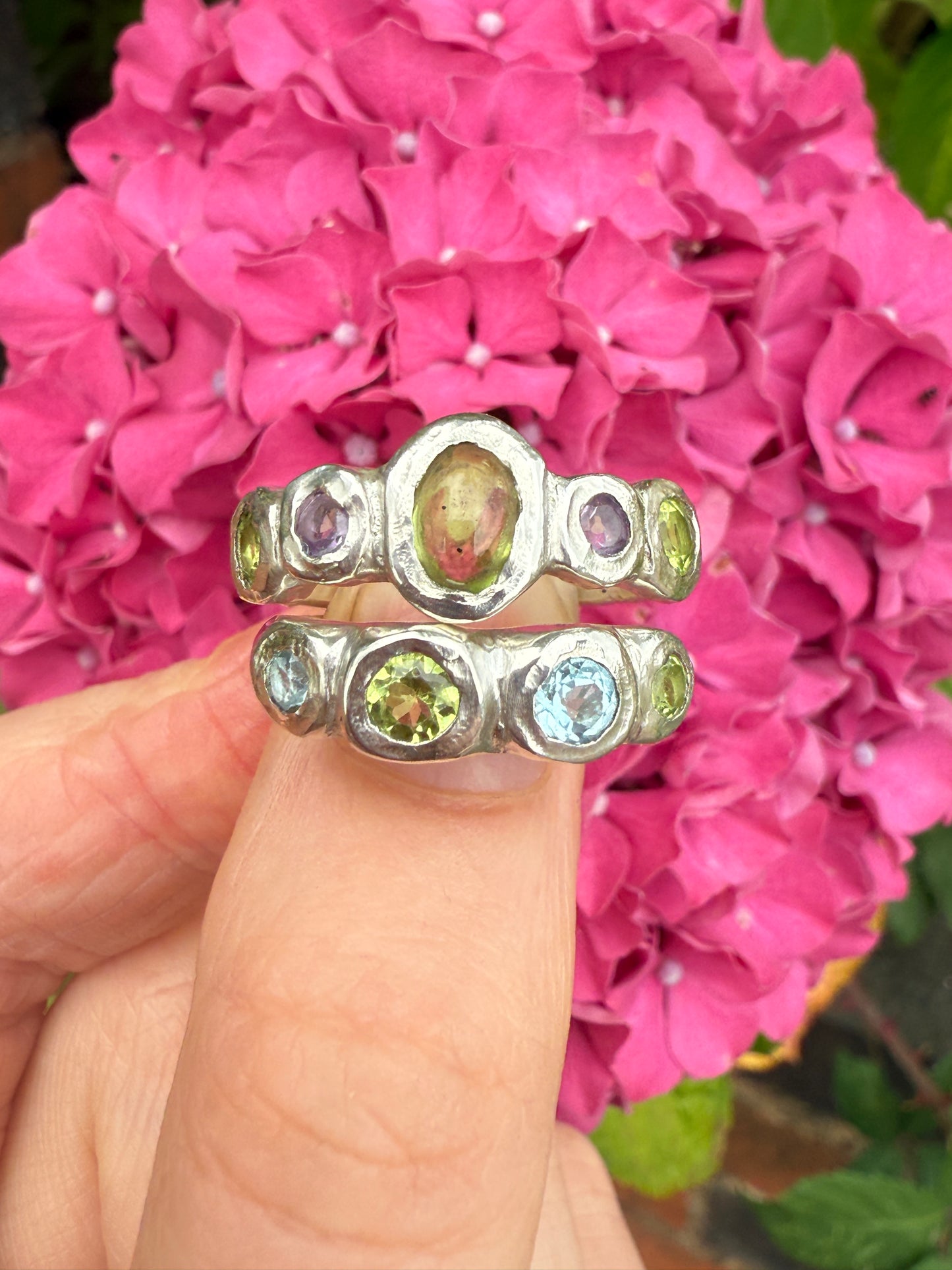 Two silver rings with green, purple and blue gemstones
