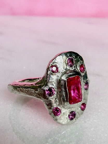Lab ruby, rhodolite and ruby handmade silver oval ring on marble surface side view