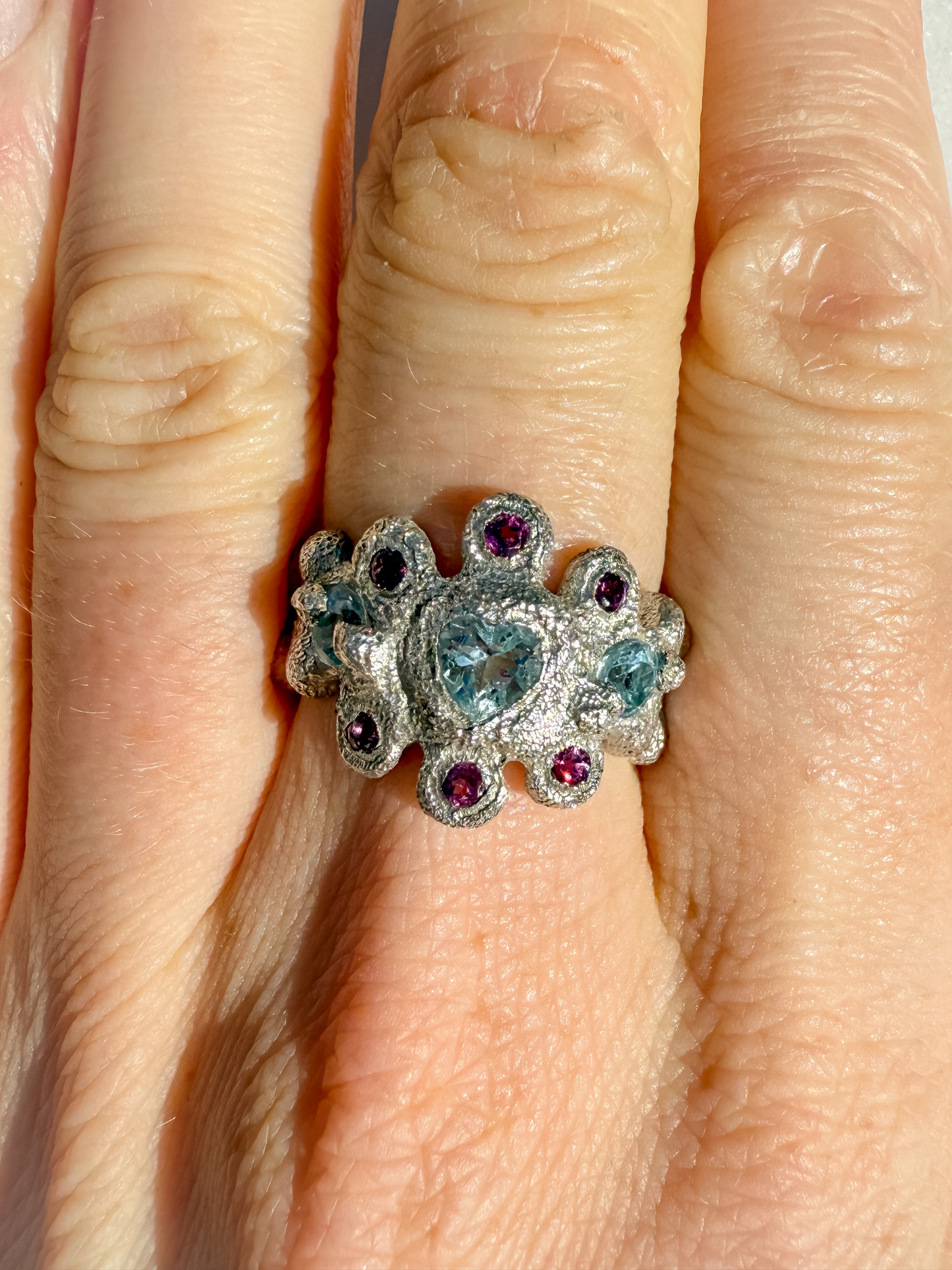 Silver ring with gemstones on a finger