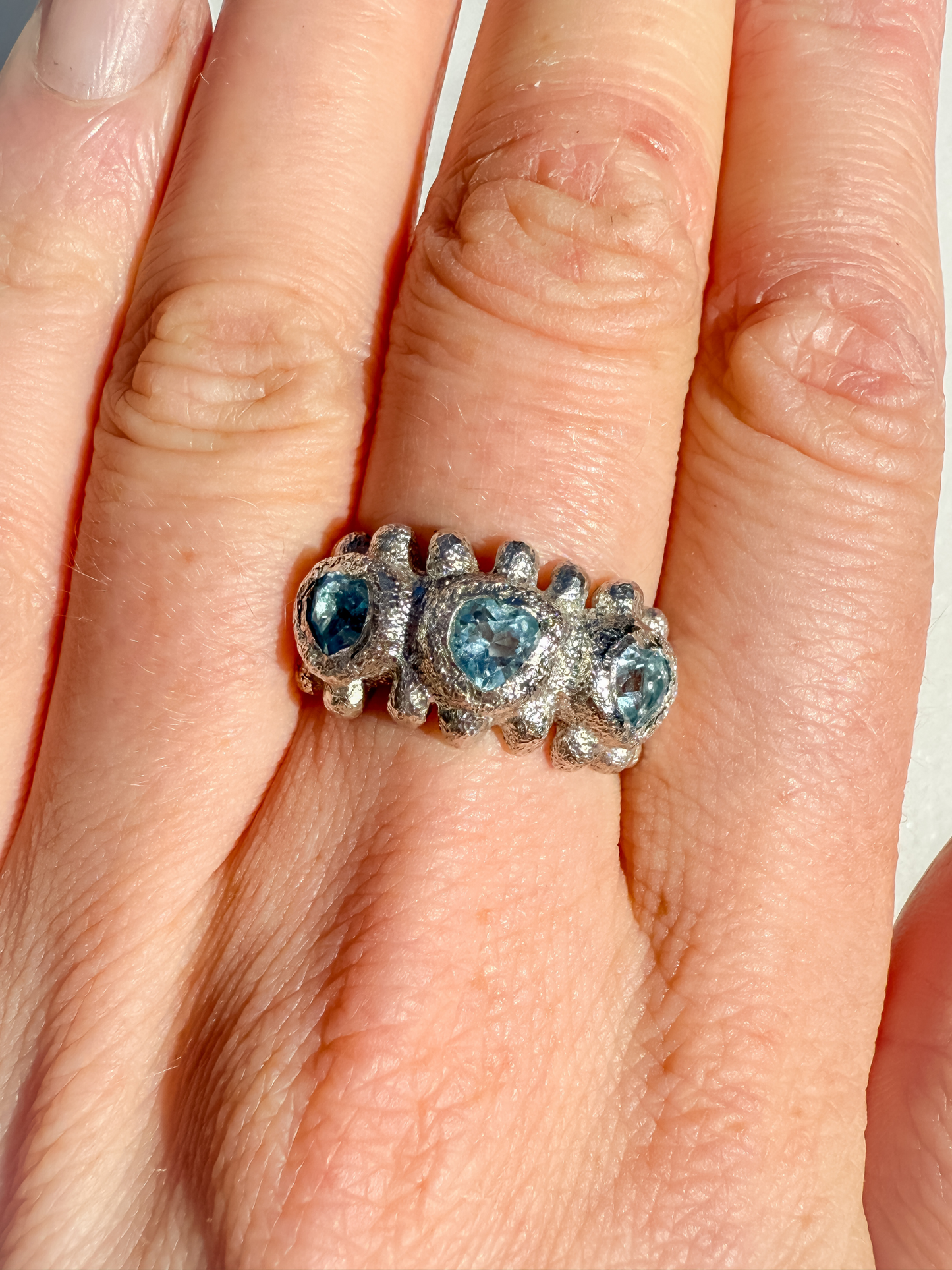 Silver ring with blue gemstones on a hand