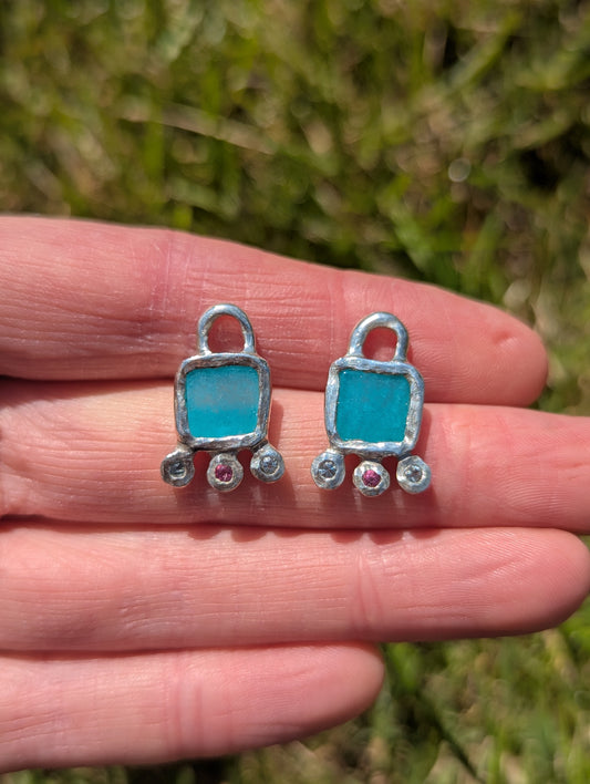 Amazonite, pink topaz and sky blue topaz hoop earring silver charms held in hand against grass