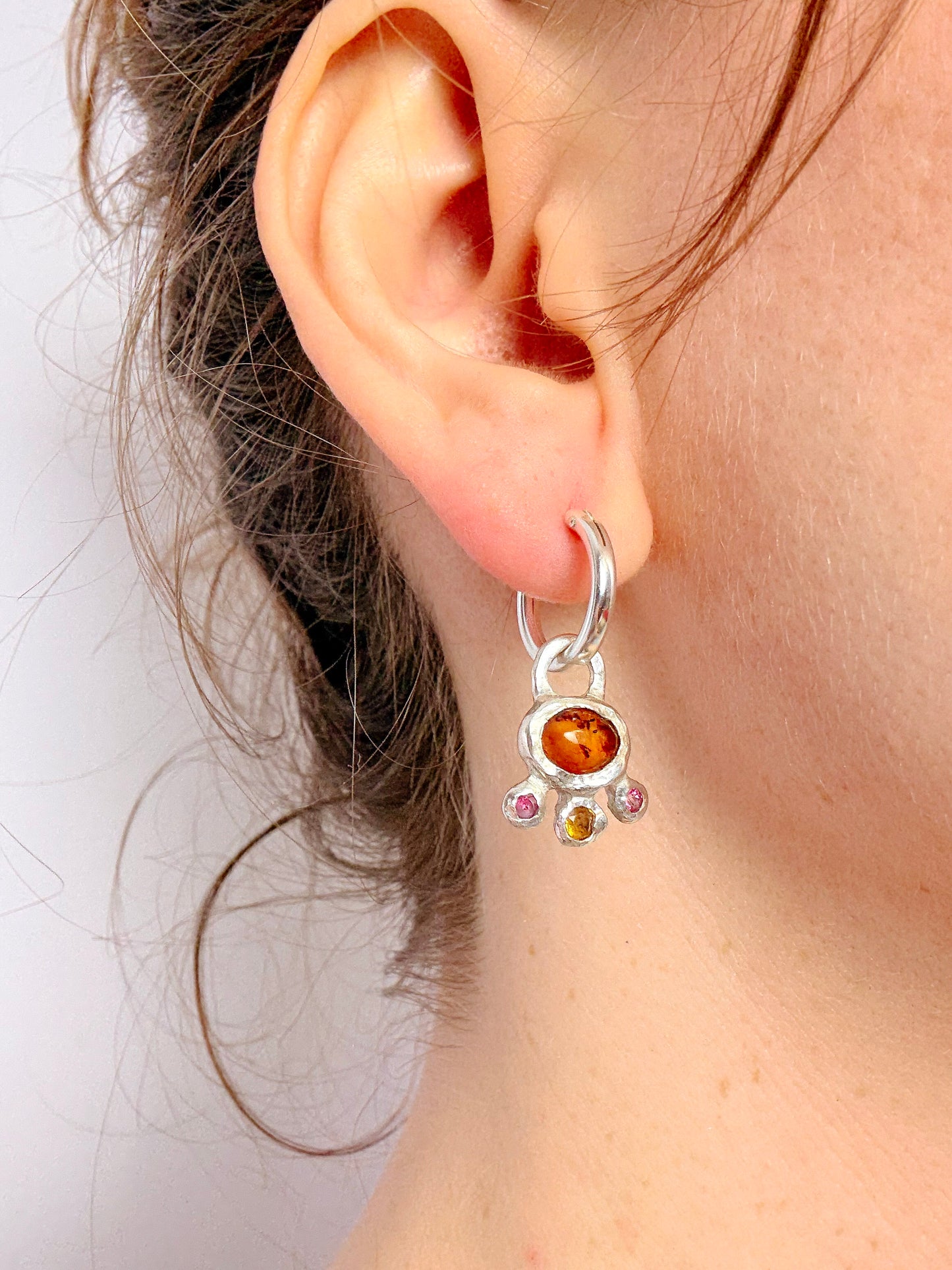 Amber and pink topaz hoop earring silver charms close up in ear