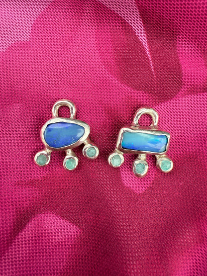 Two blue stone pendants with silver frames on a pink fabric background