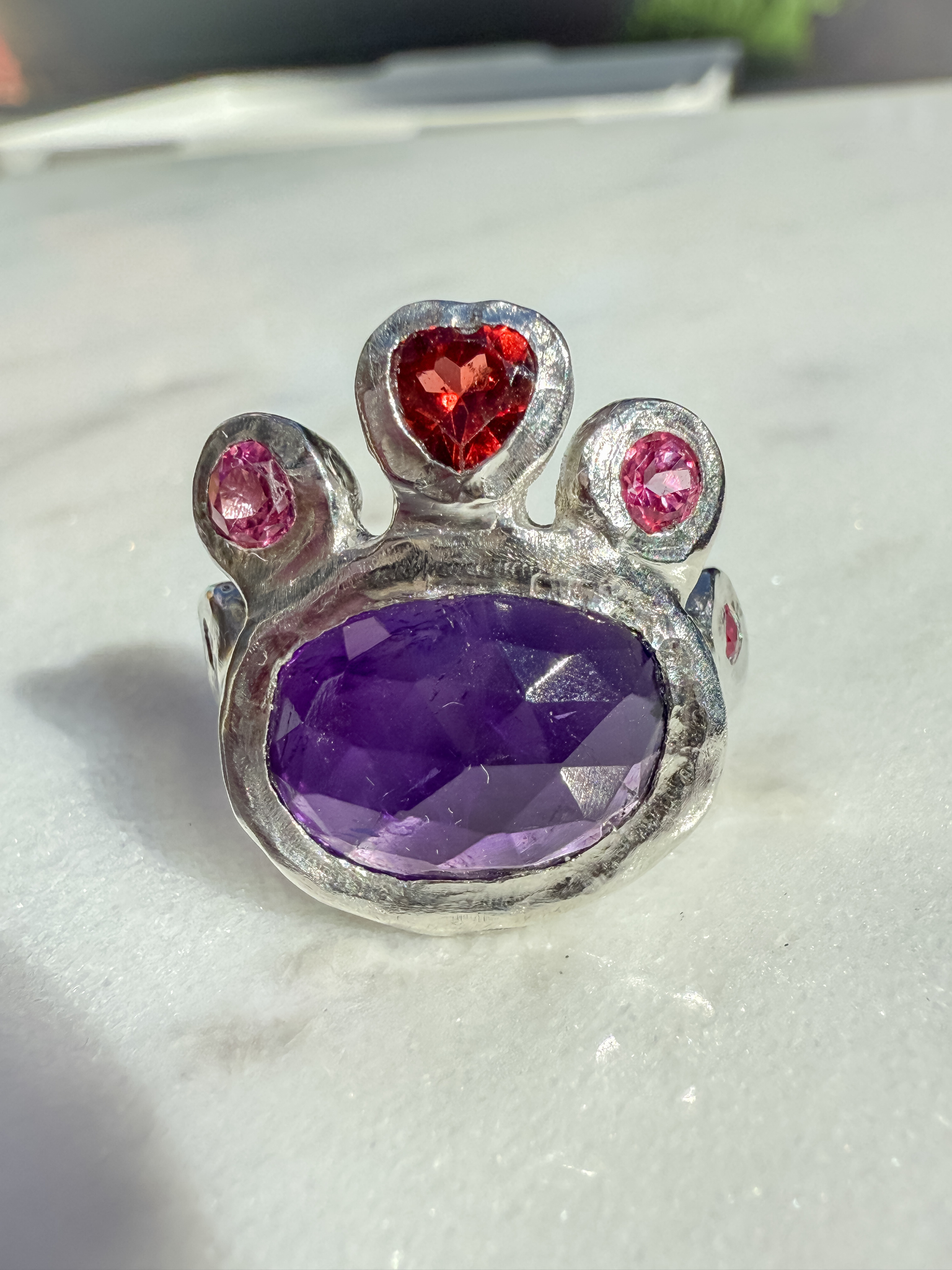 Silver with purple gemstone and red and pink stones on a light background