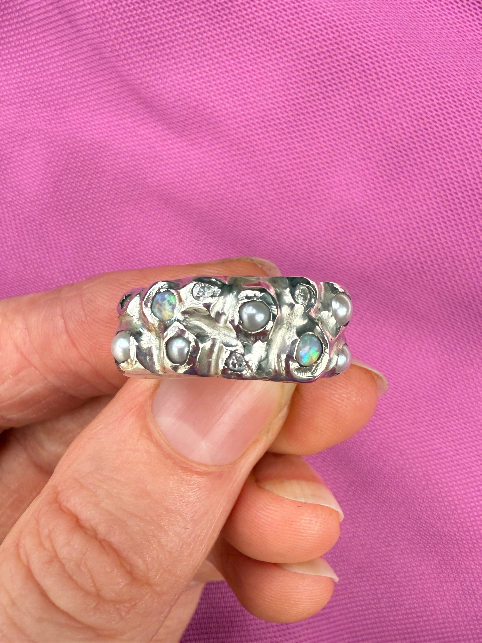 Silver ring with opals, pearls and moissanite gemstones on pink background
