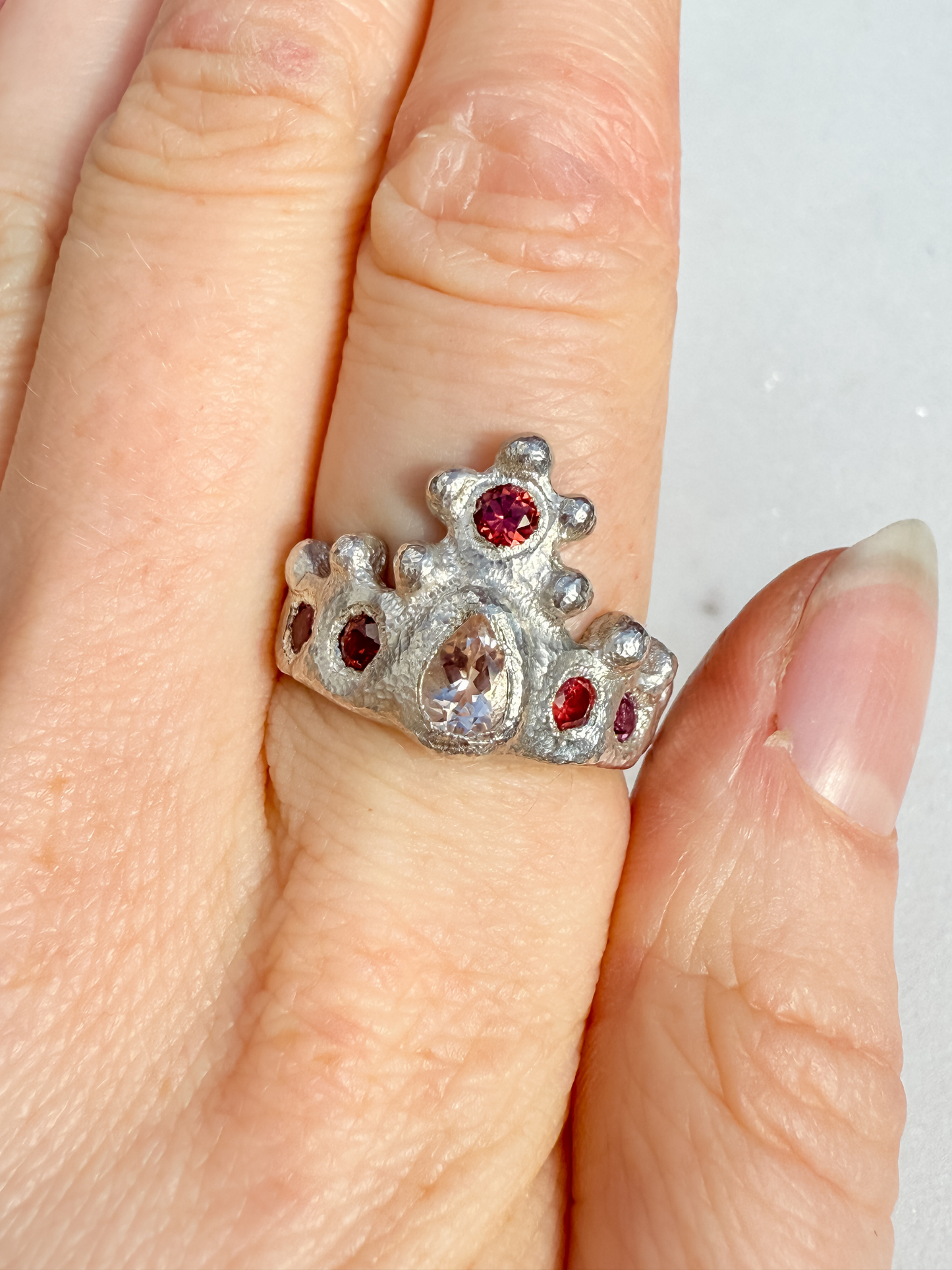 Silver crown ring with pink gemstones on a white background 2