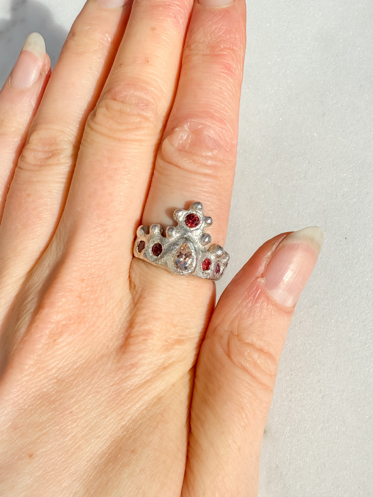 Silver crown ring with pink gemstones on a white background 3