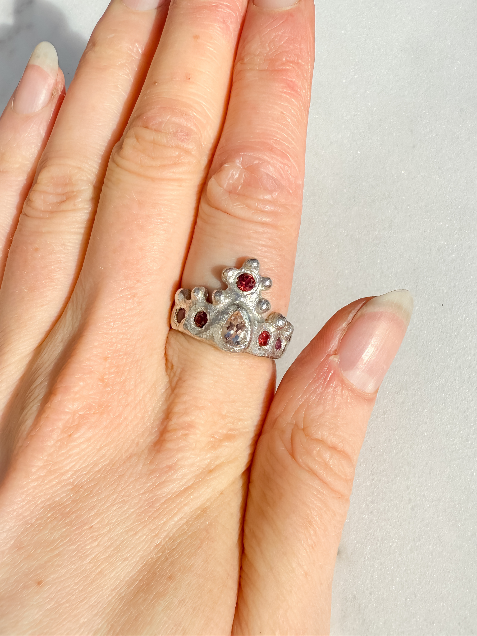 Silver crown ring with pink gemstones on a white background 3