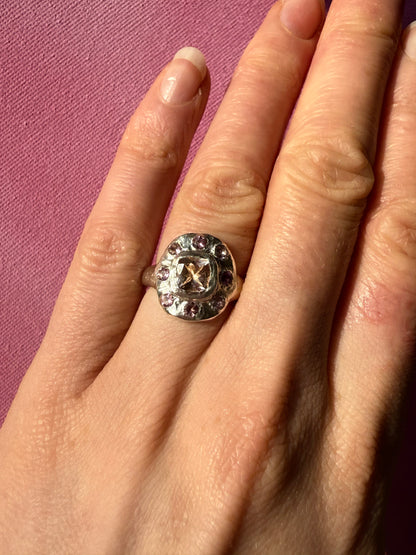 Close up of hand wearing a cushion cut peach morganite pink tourmaline handmade silver ring on pink background