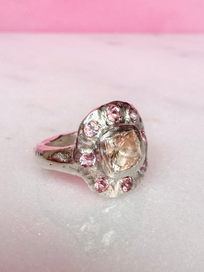 Side view of a cushion cut peach morganite pink tourmaline handmade silver ring on white and pink background 