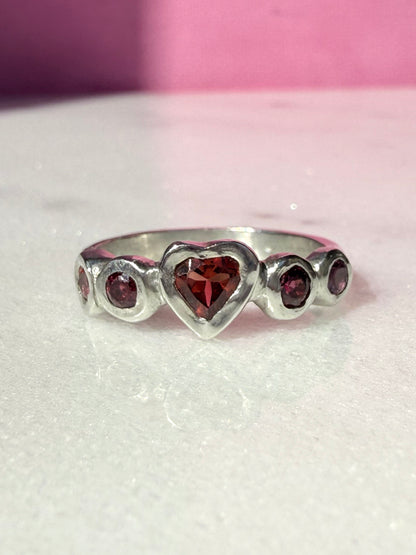 Garnet heart, rhodolite garnet, and pink tourmaline handmade silver ring on marble surface