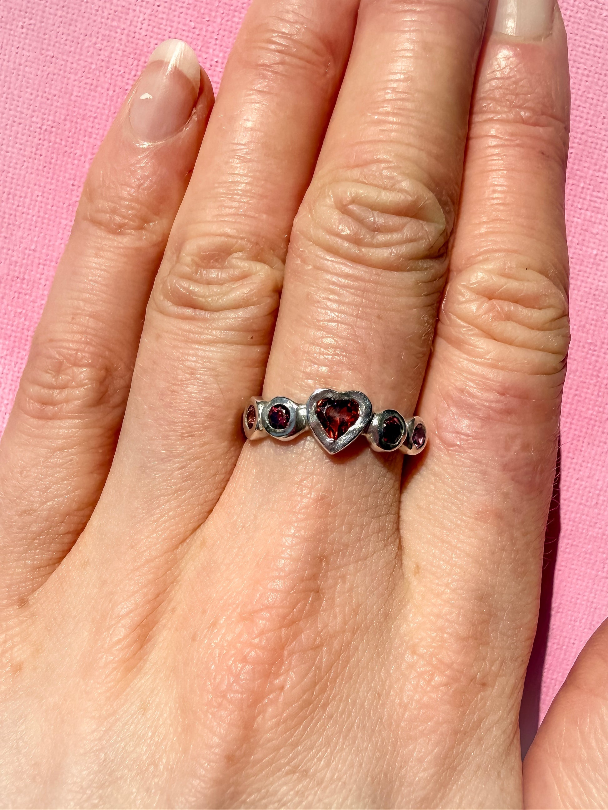Garnet heart, rhodolite garnet, and pink tourmaline handmade silver ring on hand
