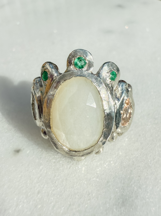 Silver ring with a large central stone and smaller stones on a light background