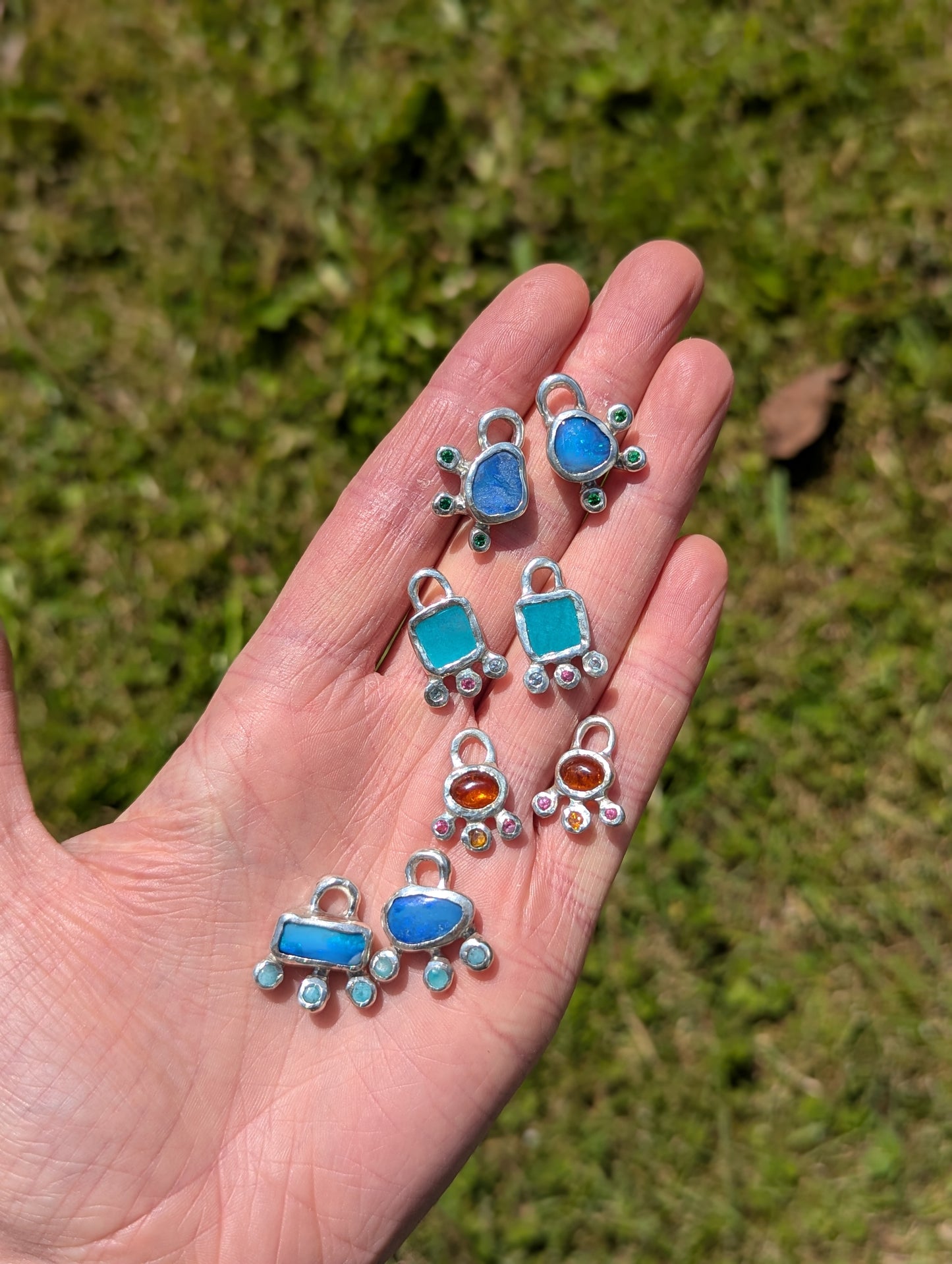 Handmade colourful earring charms held in hand against grass