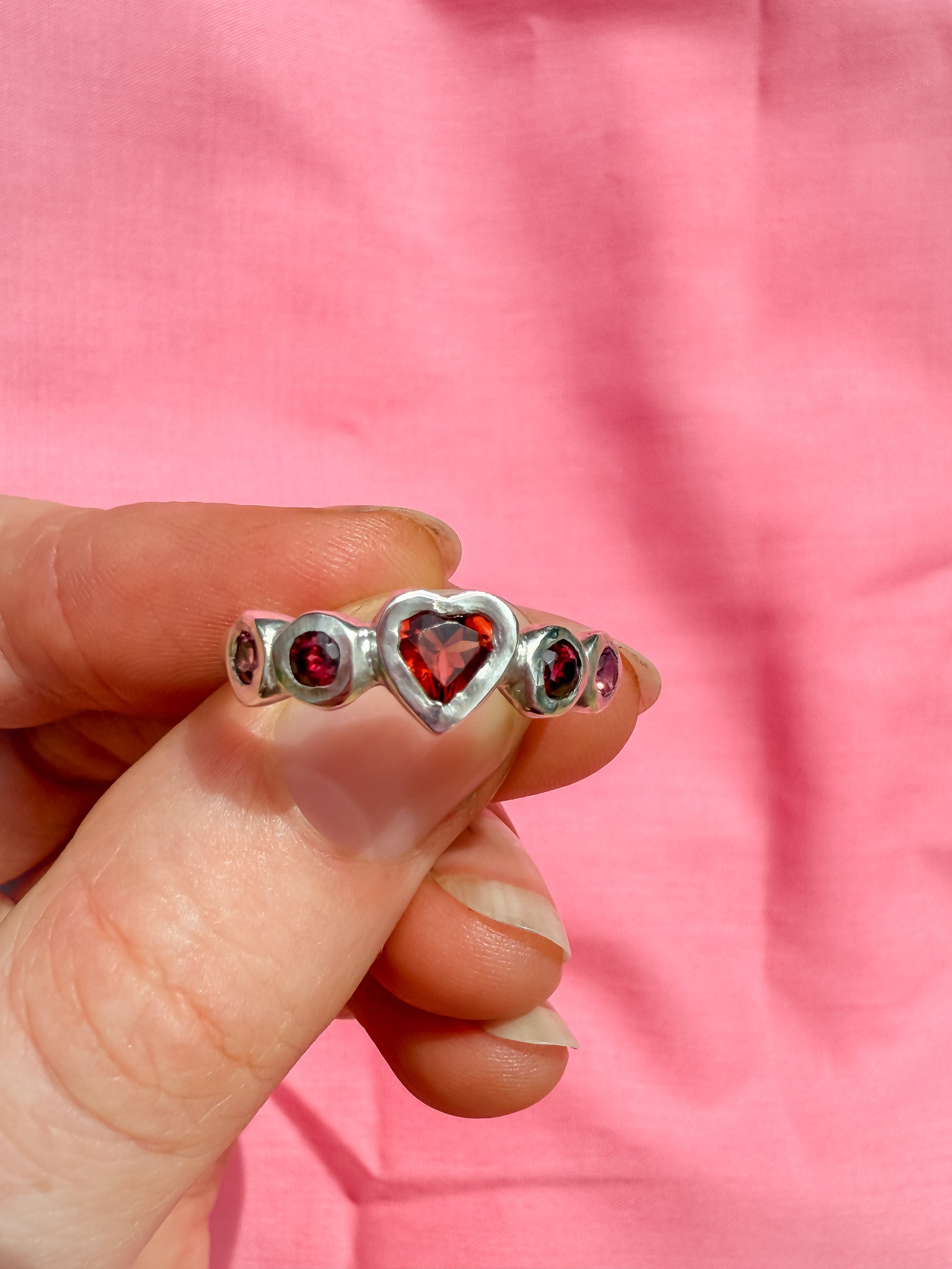 Silver ring with red heart shaped gemstones 