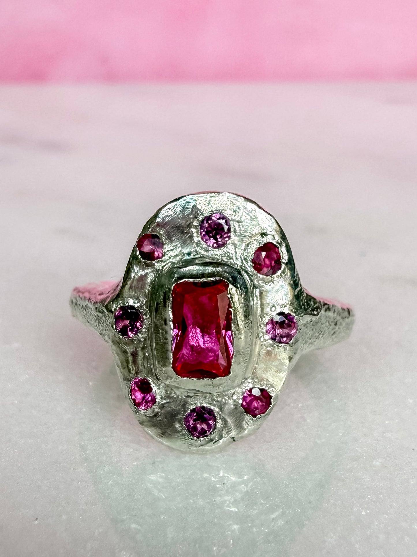 Lab ruby, rhodolite and ruby handmade silver oval ring on marble surface