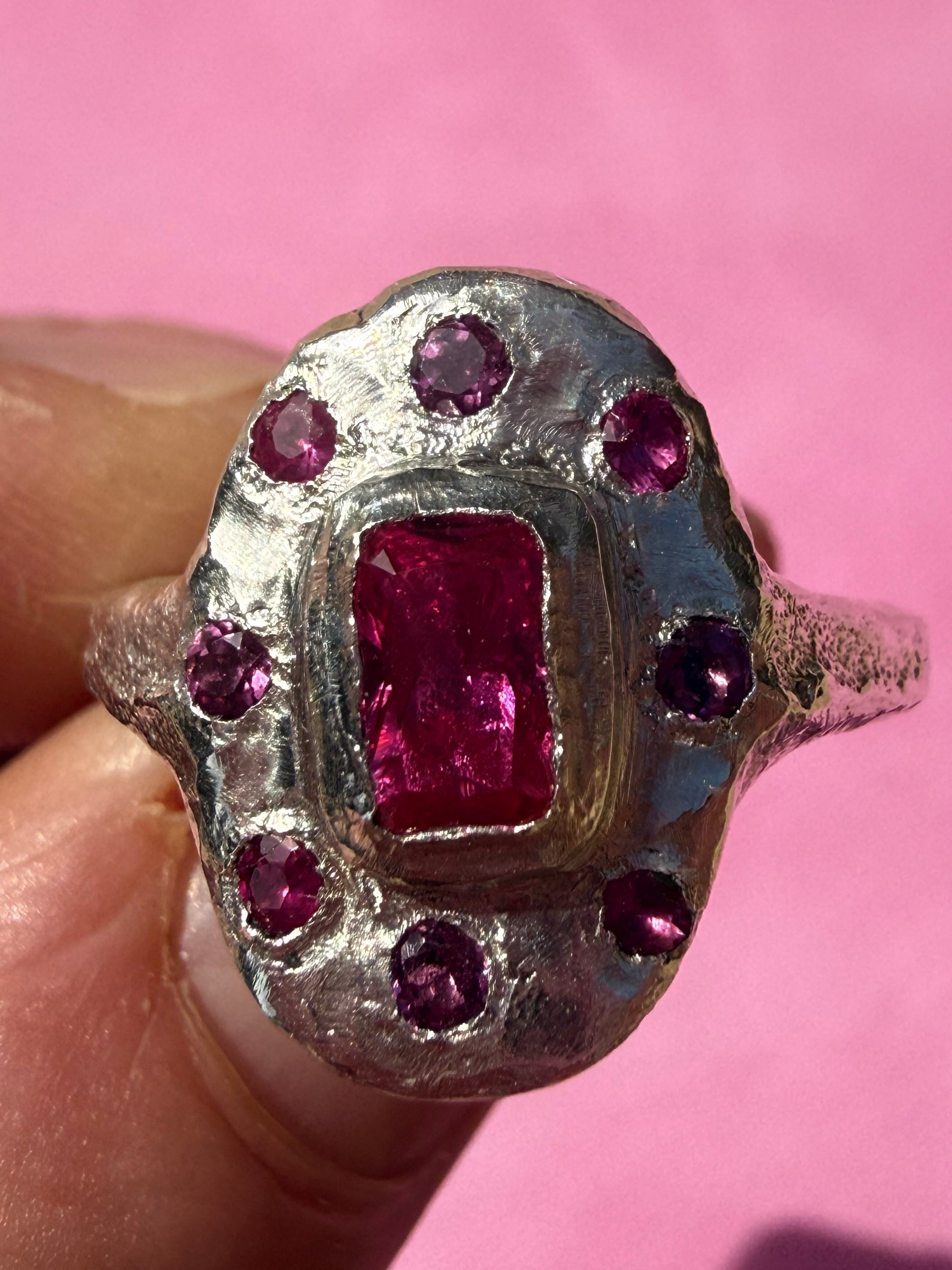 Lab ruby, rhodolite and ruby handmade silver oval ring up close sand cast texture on face of ring