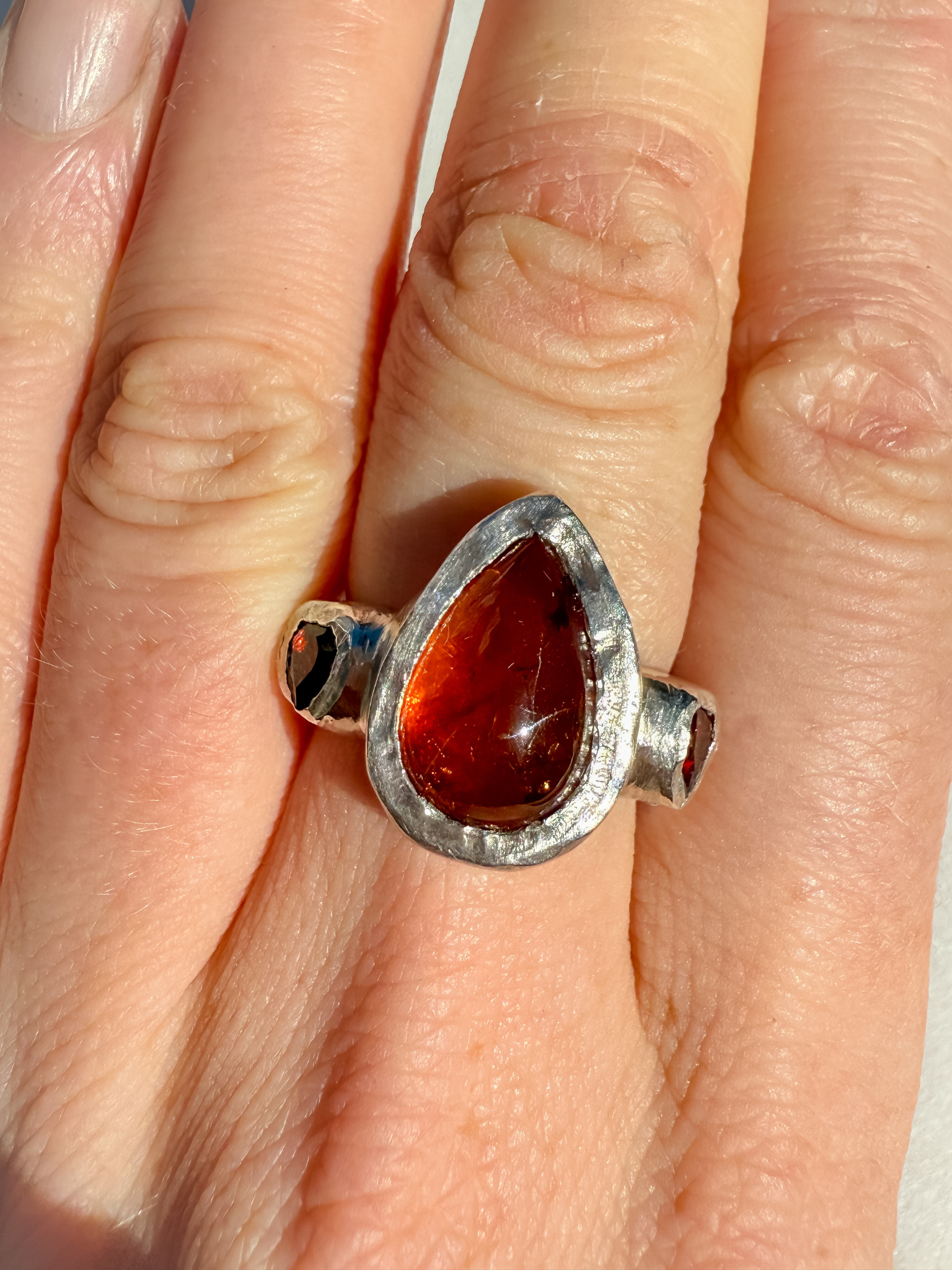 Silver ring with an amber stone on a person's finger