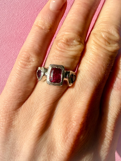 Octagon_cushion_cut_hot_pink_tourmaline_and_purple_rhodolite_heart_handmade_silver_ring_on_hand_against_pink_background