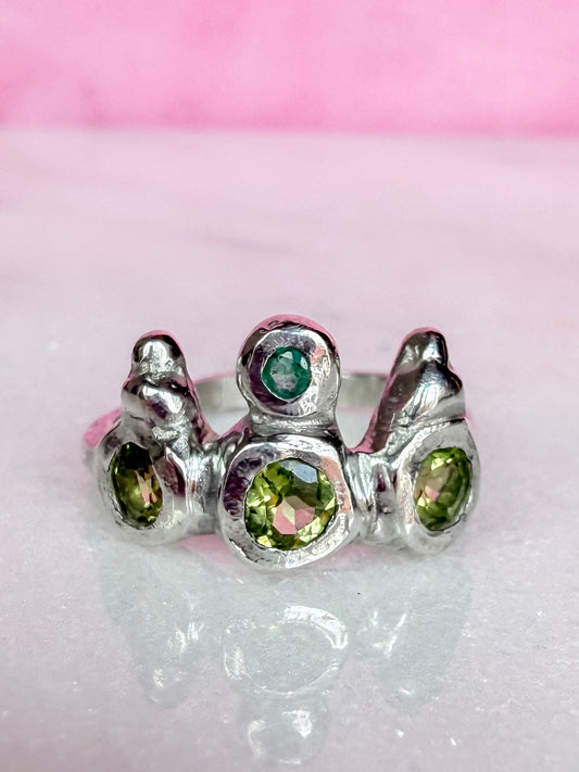 Peridot and emerald handmade silver ring on marble surface