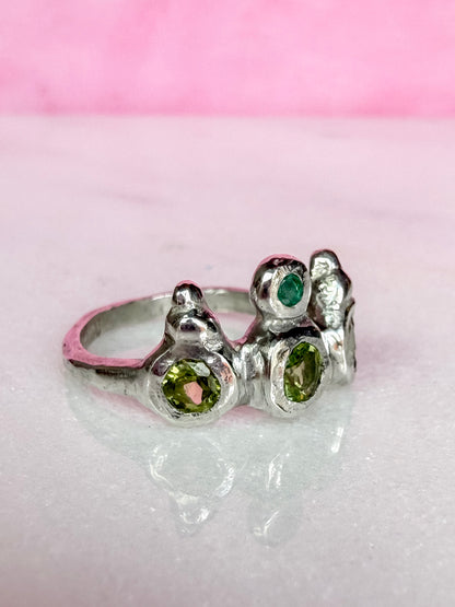 Peridot and emerald handmade silver ring side view on marble surface