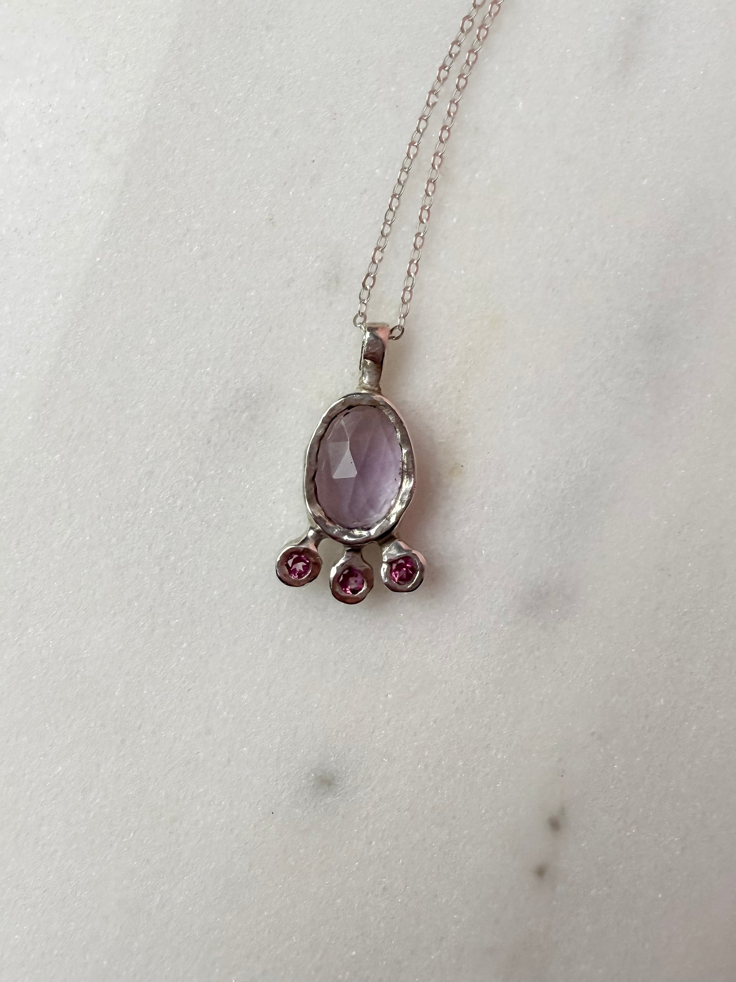 Pink amethyst slice and pink topaz silver pendant on marble surface 2