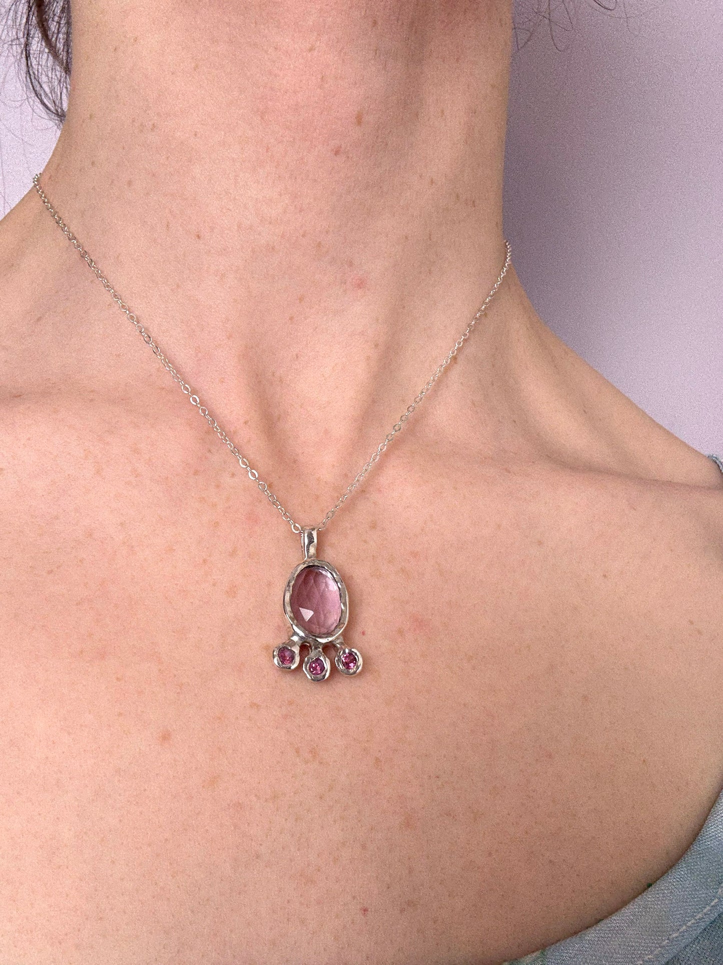 Pink amethyst slice and pink topaz silver pendant worn by a person