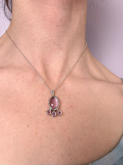 Pink amethyst slice and pink topaz silver pendant worn by a person
