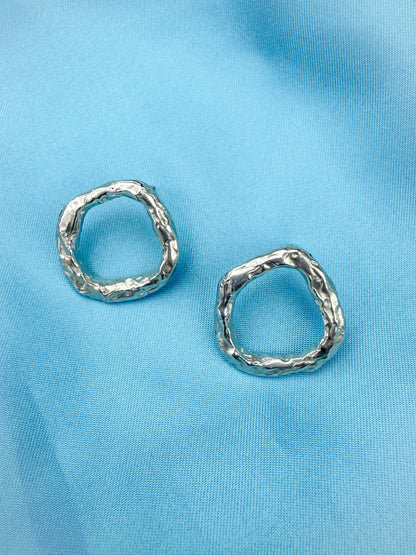 Pair of silver circle stud earrings on blue background