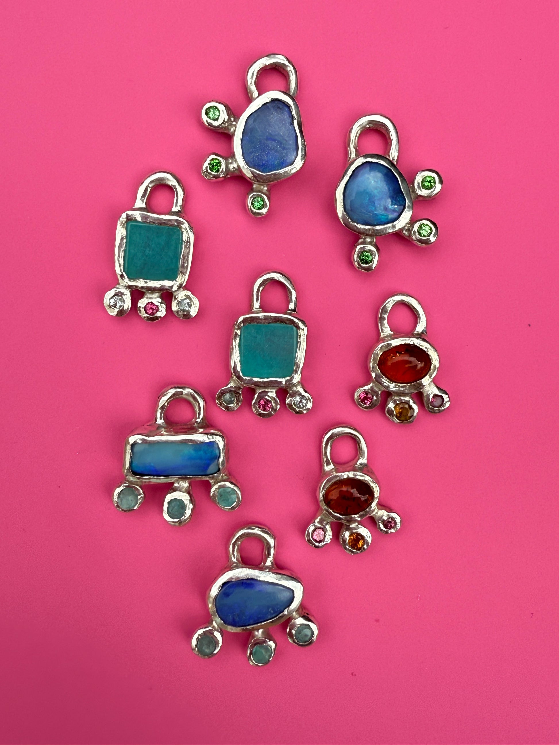 Silver earring charms on pink background