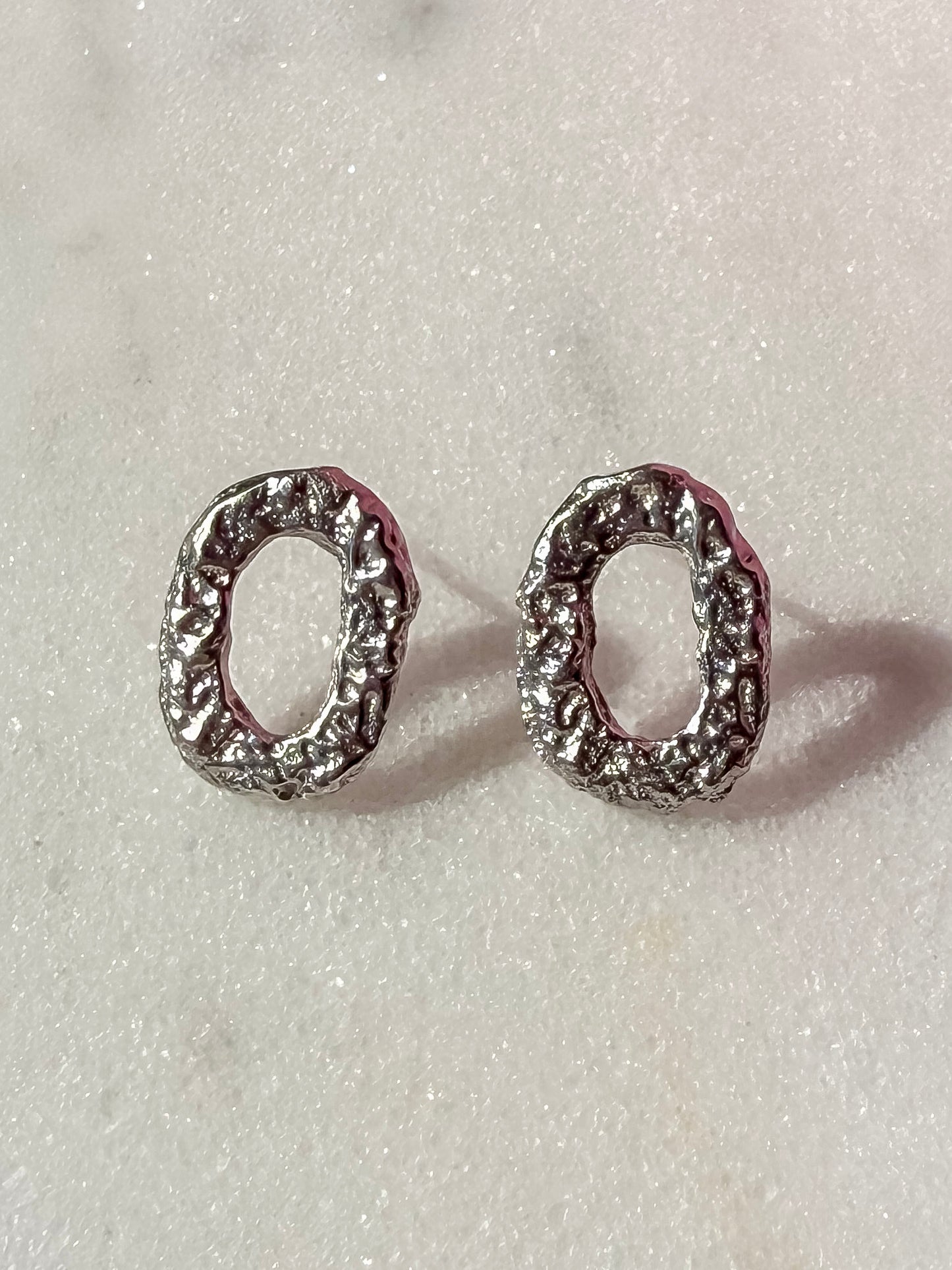 Small Textured Silver Oval Handmade Earrings on marble surface