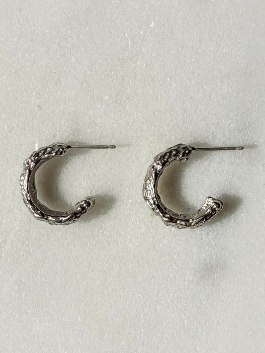 Textured silver handmade hoop earring on marble surface