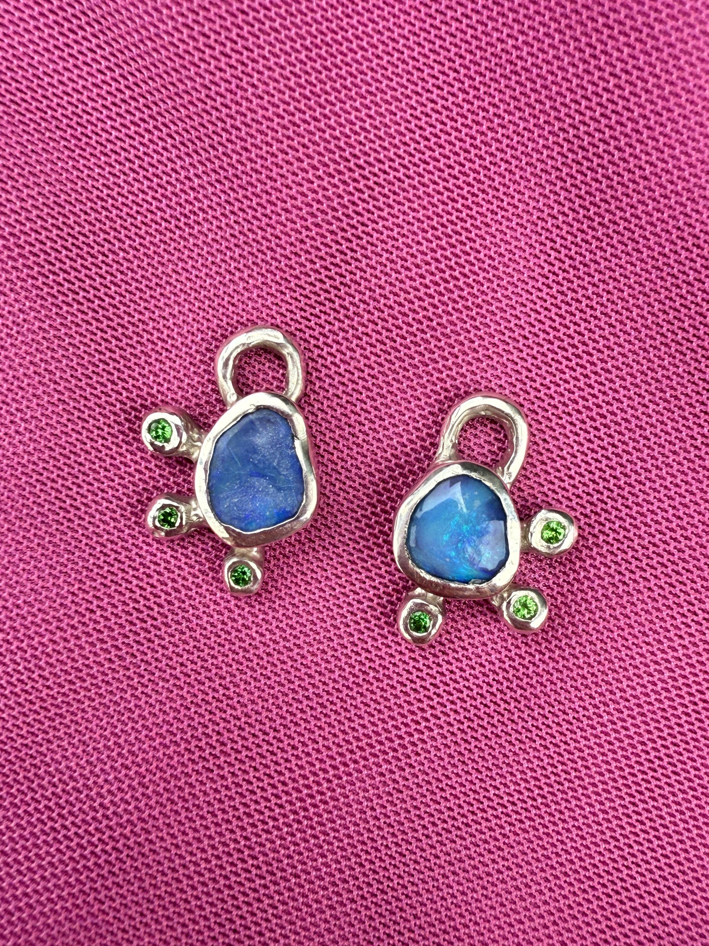 Two silver Australian opal earring charms against pink background