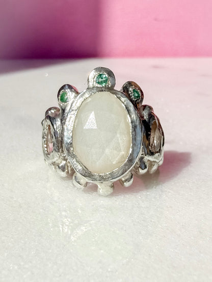 White moonstone slice, peach morganite faceted pear and emerald handmade silver ring on marble surface