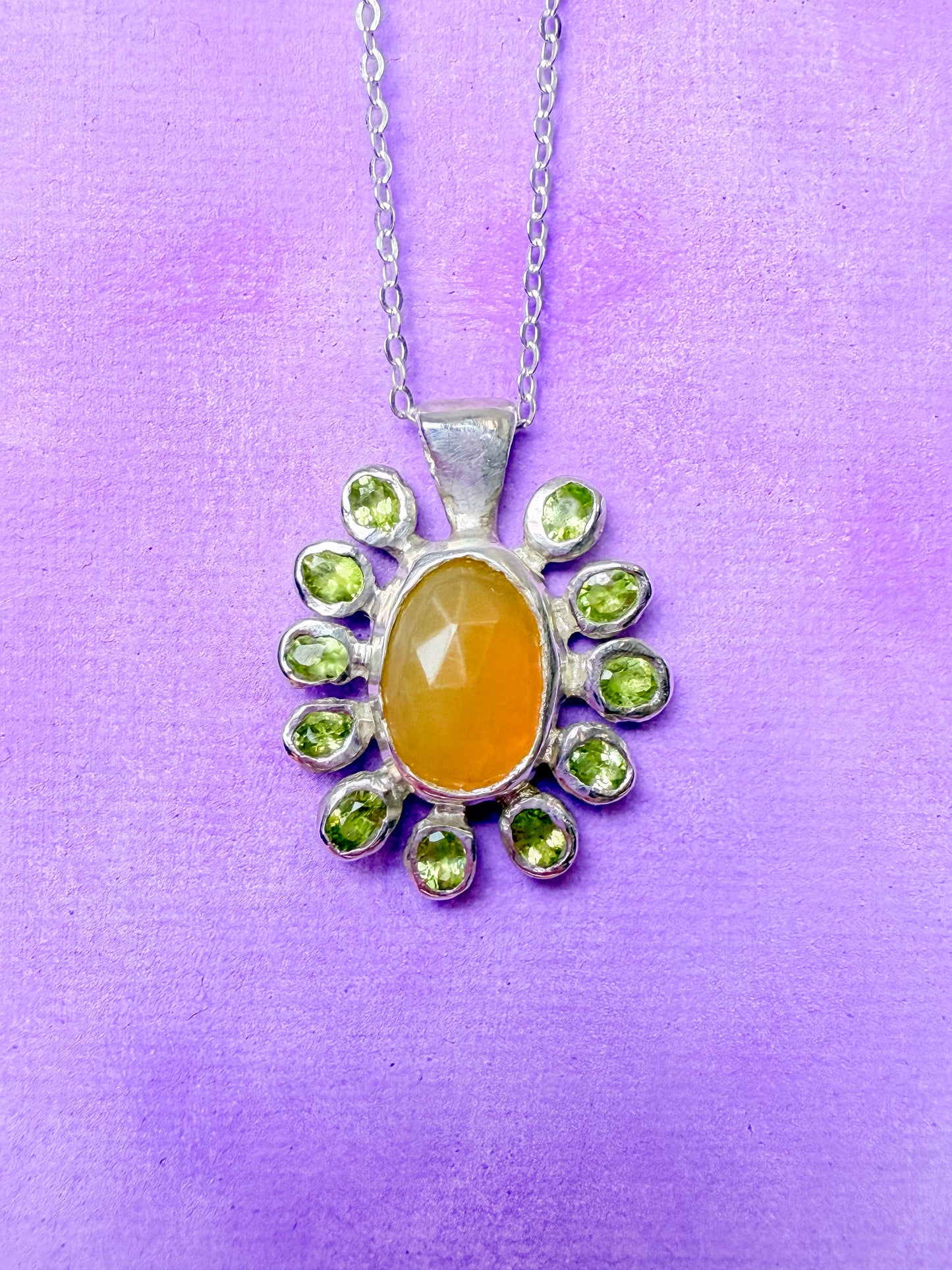 Yellow opal slice, peridot and sterling silver pendant against purple background