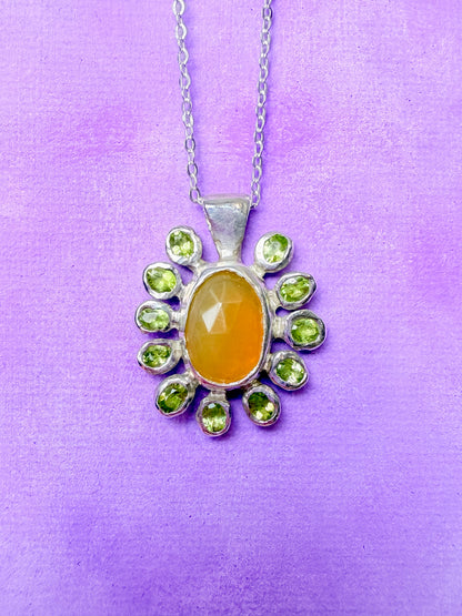 Yellow opal slice, peridot and sterling silver pendant against purple background