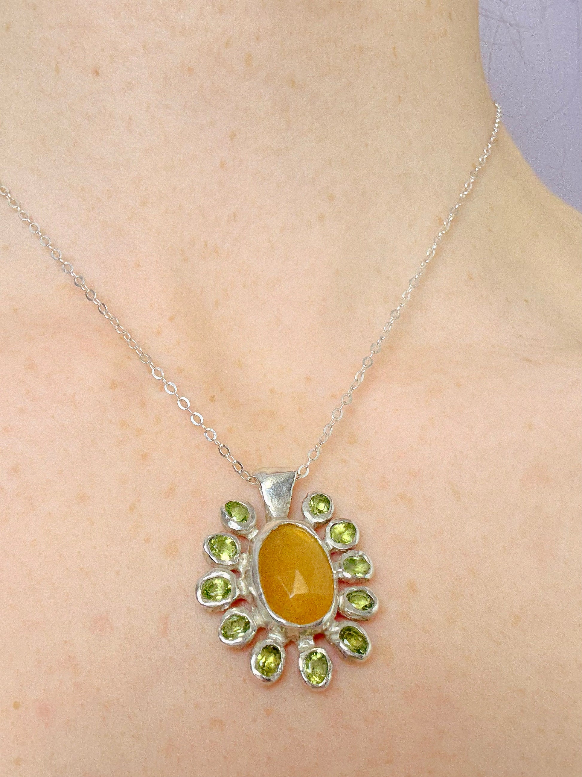Yellow opal slice, peridot and sterling silver pendant on a person's neck