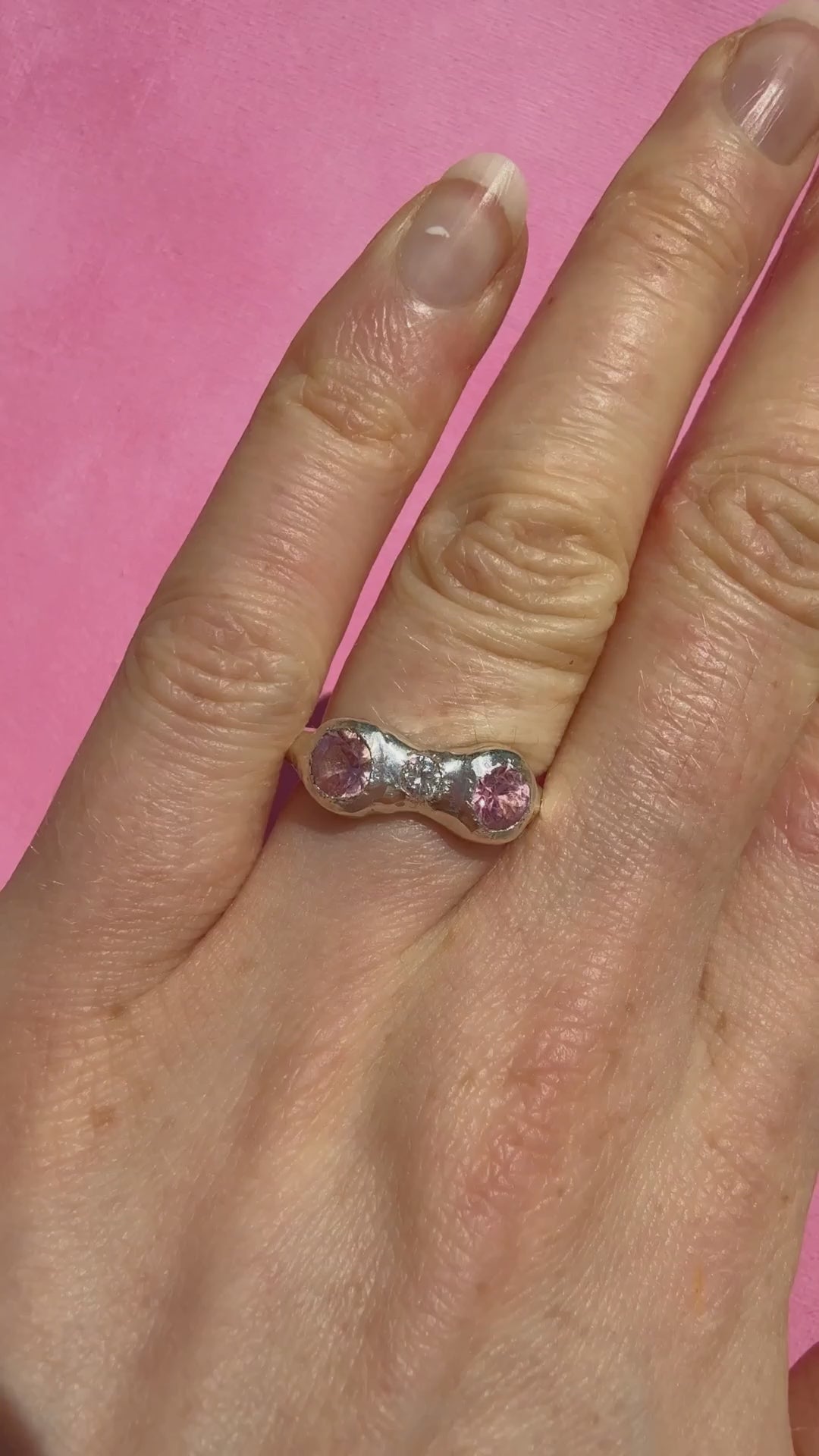 Natural pink tourmaline and lab-grown moissanite handmade silver ring on hand sparkling in the sun