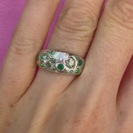 Green sapphire, emerald, tsavorite garnet and moissanite handmade silver ring on hand sparkling in sunlight